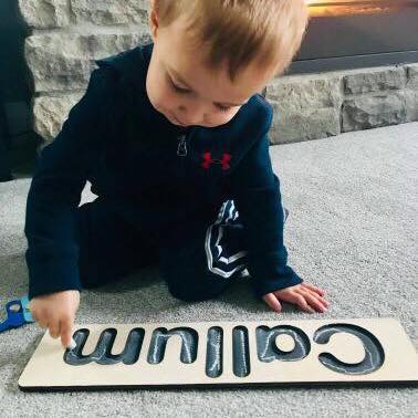 Child using customized chalkboard name puzzle for handwriting practice